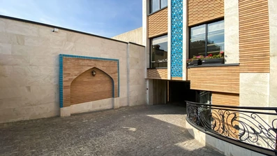 حیاط یک ساختمان با نمای قهوه ای و خطوط آبی باریک در هتل آوات اصفهان