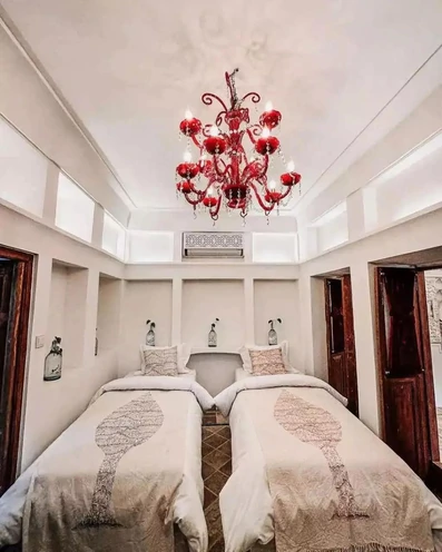 دو تخت یک نفره و لوستر قرمز سنتی در خانه بهشتیان اصفهان