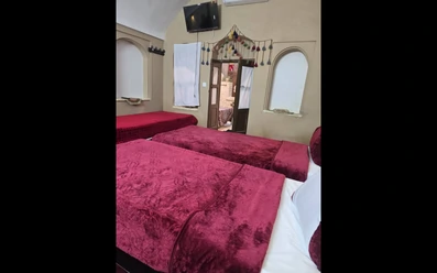 اتاق 3 تخته با دیوارهای نما کاهگل و تلویزیون در اقامتگاه بومگردی چهار قنات یزد