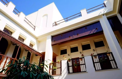 نمای سفید اقامتگاه سنتی دنسه ریحان بوشهر با در و پنجره های چوبی