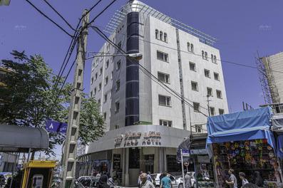 نمای سنگ‌کاری شده سفید ساختمان 9 طبقه هتل عماد مشهد که سر دو نبش خیابان است