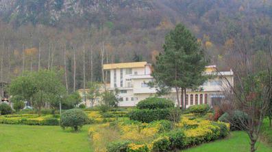 نمای سفید رنگ هتل فجر آبشار در میان درختان و فضای سرسبز اطراف