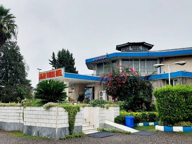 ساختمان سفید و آبی هتل جهانگردی لاهیجان با گلکاری در جلوی ورودی