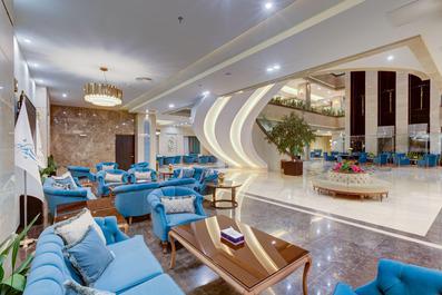 تصویری از مبل های راحتی آبی فیروزه ای در لابی هتل که کف آن سنگ های زینتی درخشان قرار دارد.