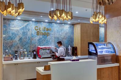 یک باریستا در حال کار با دستگاه قهوه ساز با بدنه قرمز رنگ در کافی شاپ هتل هشتم کوثر مشهد