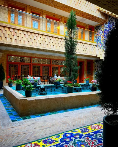 حوض فیروزه ای با گلدان هایی روی آن در حیاط بوتیک هتل ماه گیسو شیراز