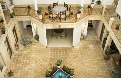 حیاط اندرونی اقامتگاه سنتی معمار کاشان با صندلی های چوبی و گلدان