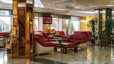 مبل های راحتی با چرم قرمز در فضایی با کف سنگی براق و لوکس که متعلق به لابی هتل قصر ضیافه مشهد است.