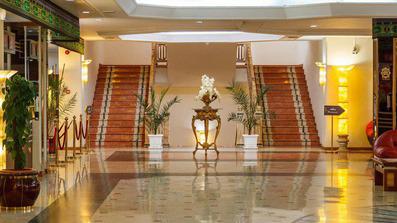 دو پلکان سنگی با رنگ سنگ قرمز در هتل قصر ضیافه مشهد. کف سنگی براق و لوکس در این تصویر ه خوبی به چشم میخورد.