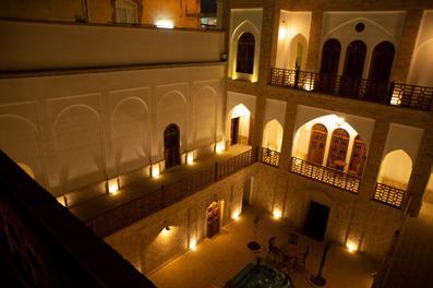 نمای بیرونی اقامتگاه سنتی سنگ پلوی کاشان در شب با چراغ های زرد رنگ