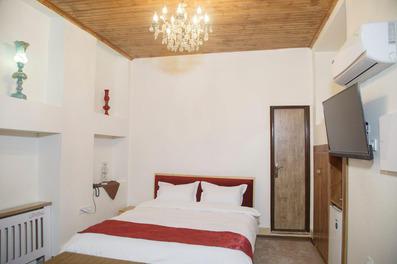 یک تخت دو نفره با ملحفه سفید در اتاق دو نفره سرای خان گرگان