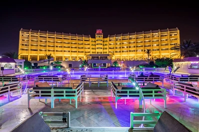 نمای هتل شایان کیش با نورپردازی های زیبا در شب به همراه تخت در محوطه