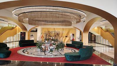 مبل های راحتی سبز رنگ در لابی هتل سیب و نار یزد که کف آن با فرش قرمز پوشانده شده است.