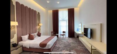 تخت دو نفره با ملحفه سفید و رو تختی قهوه ای رنگ در اتاق دوتخته دابل هتل سیب و نار یزد