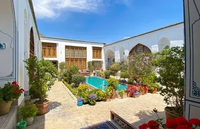 حیاط هتل سنتی اصفهان با یک حوض مرکزی و تعداد زیادی گل و گلدان