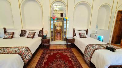 یک تخت یک نفره و یک تخت دو نفره با ملحفه سفید و ظاهر سنتی هتل سرخه ای تبریز