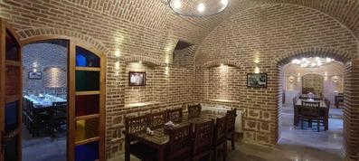 دو دست میز و صندلی در رستوران هتل سرخه ای با ظاهر سنتی و نمای دیوار آجری