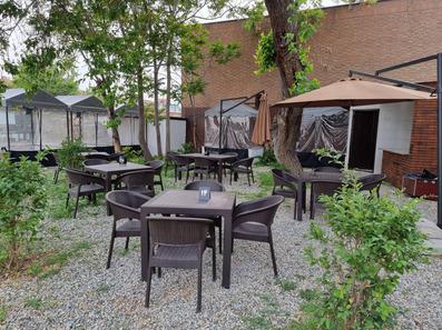 چند میز و صنئلی قهوه ای رنگ در رستوران فضای باز هتل ترن تهران