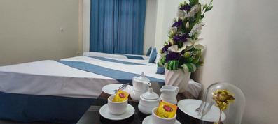 اتاق 3 تخته با سه تخت یک نفره که ملحفه سفید و رو انداز آبی فیروزه ای دارند. پنجره اتاق با پرده آبی تزیین شده است.