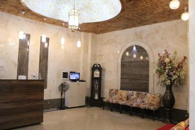 لابی هتل احمد بندر انزلی با سنگ های روشن در کف و دیواره ها، سقف طلایی رنگ با لوستر جذاب در تصویر دیده می شود.