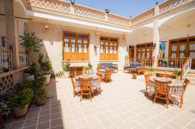 فضای نشیمن روز باز در حیاط سرای سه سوک کاشان که میز و صندلی های سنتی چوبی در آن به چشم میخورد.