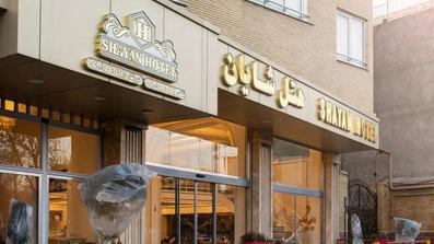 نمای آجری ساختمان مربوط به یک هتل که درختان کوچک در آن دیده می‌شوند.